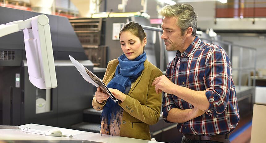 Man in printing house showing client printed materials
